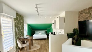 A compact living space with a bed, a dining area, a TV, and a kitchen area. - Catullo Loft (Dossobuono)