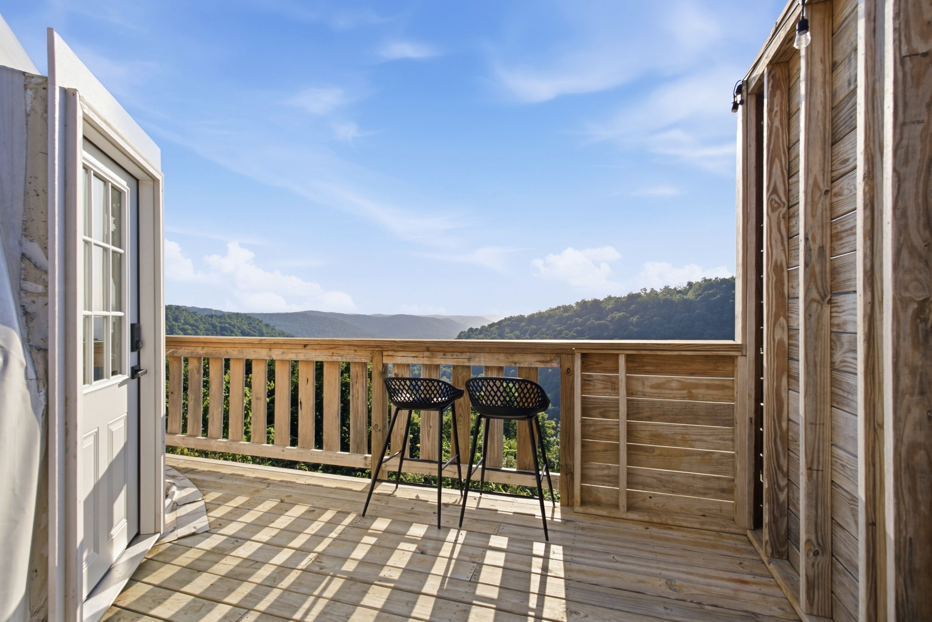 Una terraza de madera con dos sillas y vistas a un paisaje montañoso.