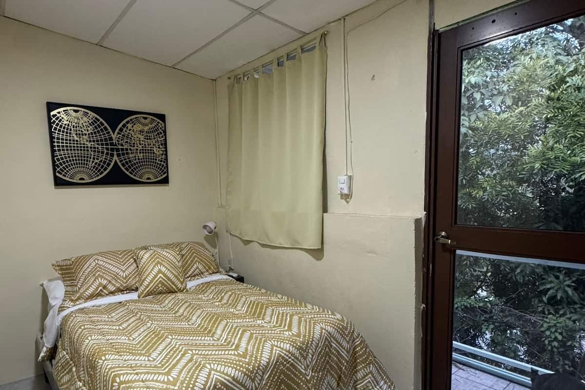 Un dormitorio con cama, ventana con cortinas, un globo decorativo en la pared y suelo de baldosas.