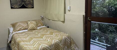 A bedroom with a bed, a window with curtains, a wall-mounted globe decoration, and a tiled floor.