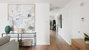 Ein modernes Wohnzimmer mit einer Couch, einem Couchtisch und einem großen abstrakten Gemälde.