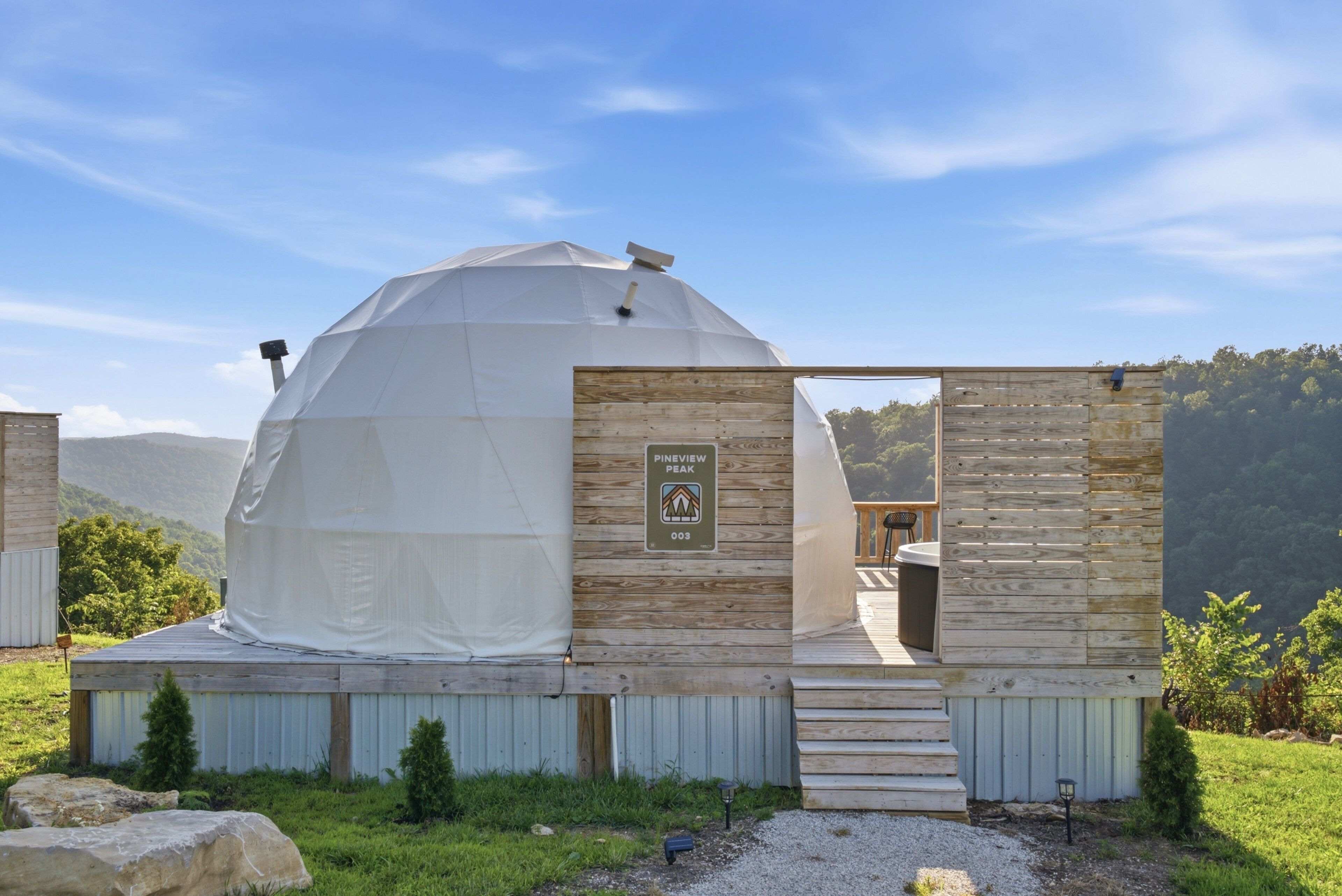 A geodesic dome structure with a wooden entrance and a sign indicating a pin review peak.