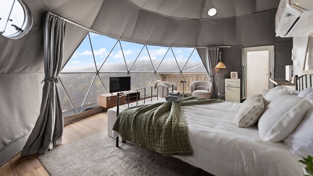 Ein geräumiger Zeltraum mit Bett, Schreibtisch, Stuhl und Fernseher.