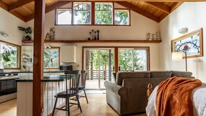A spacious kitchen with a dining area, a sofa, and a large window overlooking greenery.