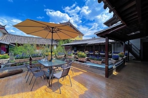 Un patio al aire libre con mesa y sillas, un paraguas grande y una piscina.