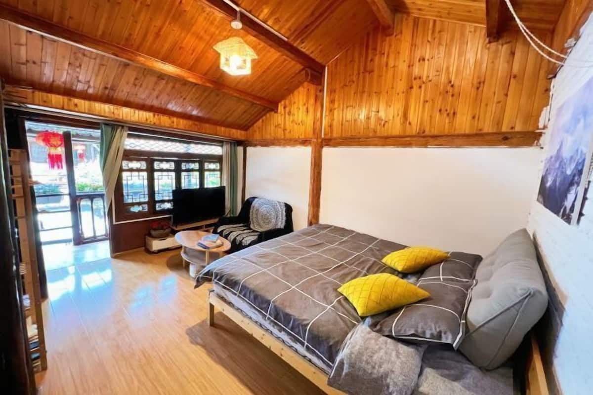 A wooden-paneled room with a bed, a small table, and a TV.