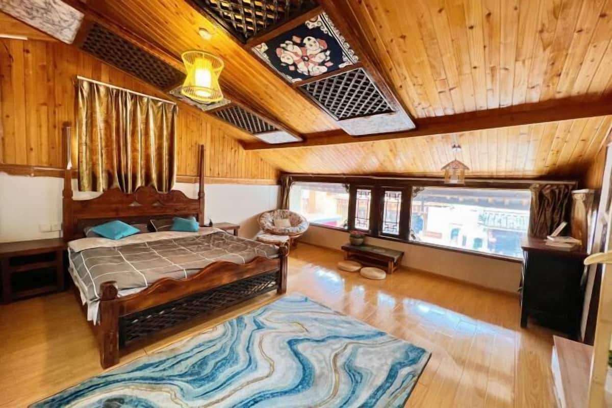 A wooden room with a bed, a chair, a bench, and a window.