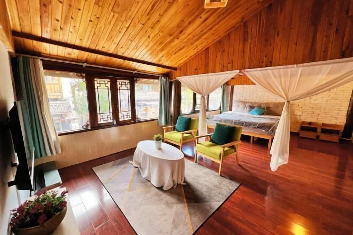 A wooden room with a bed, a round table, and two chairs.