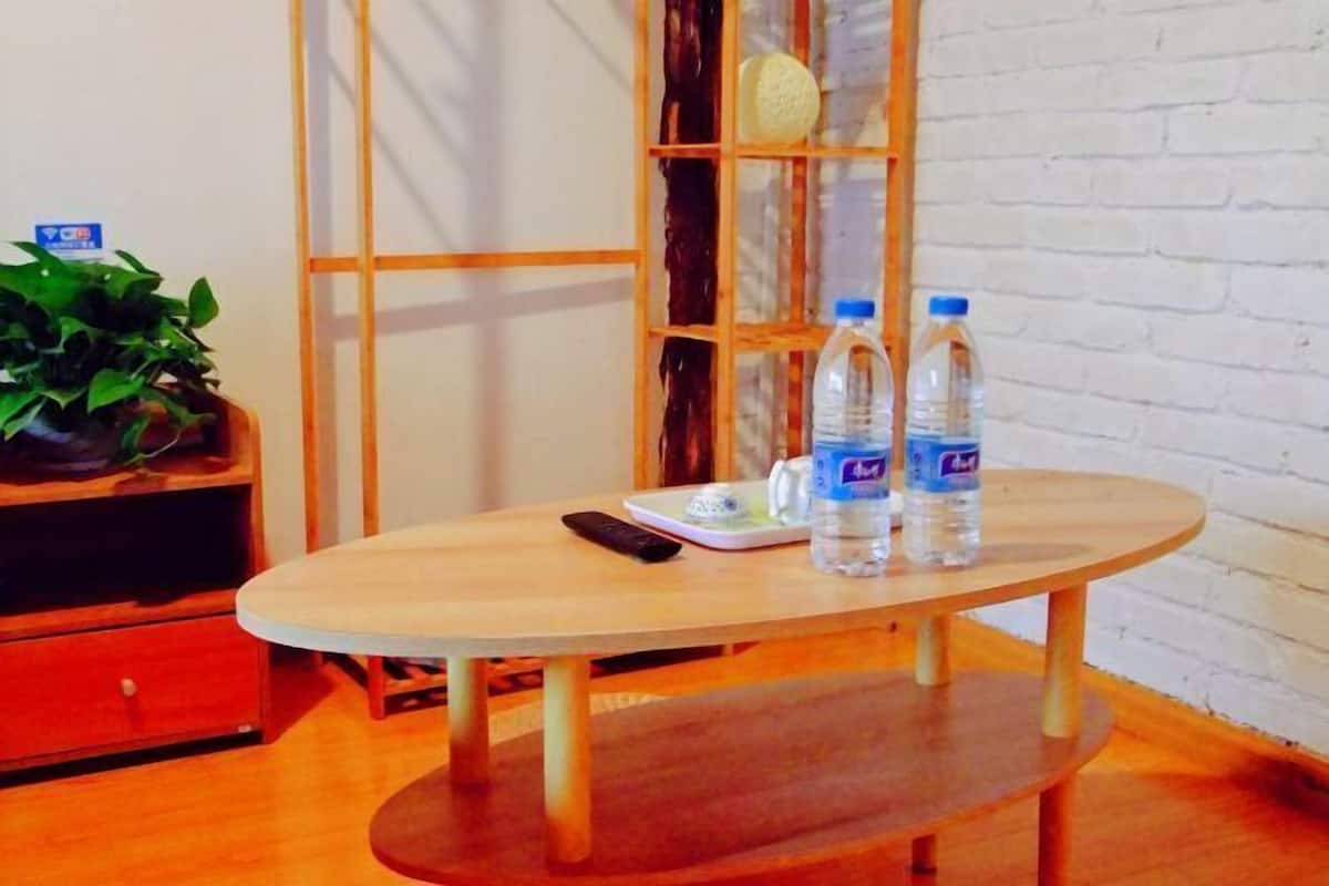 A round wooden table with two water bottles and a remote control.