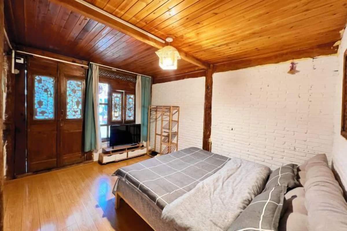 A wooden-paneled room with a bed, a TV, and a white brick wall.