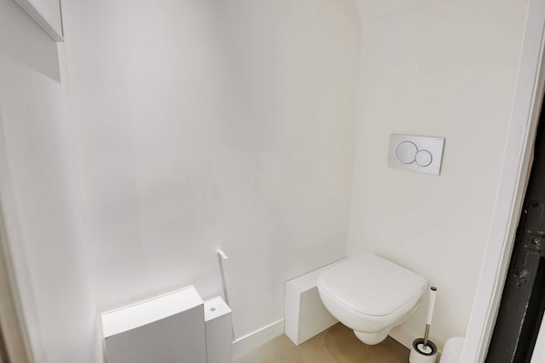A small, white bathroom with a toilet, a bidet, and a wall-mounted flush handle. - Duplex Loft Montmartre -18th (Paris)
