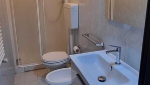 A modern bathroom with a shower enclosure, a toilet, and a sink with a mirror. - Paradise Inn 2 (Livorno)