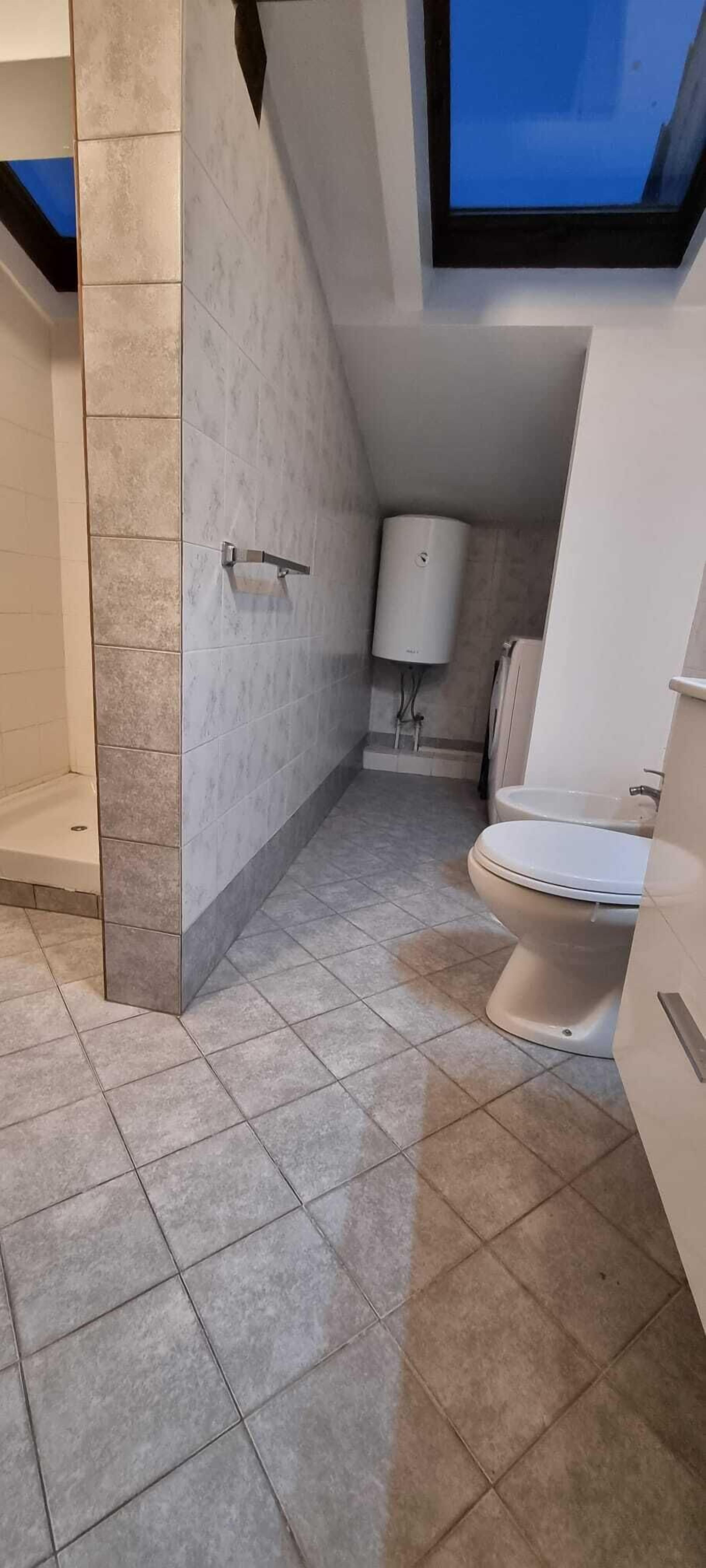Ein modernes Badezimmer mit Toilette, einem weißen Waschbecken und einer Duschkabine.