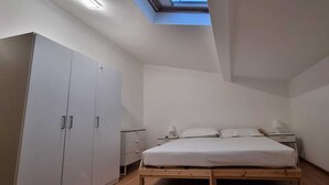 A bedroom with a skylight, a bed, a wardrobe, and bedside tables. - Paradise Inn 2 (Livorno)