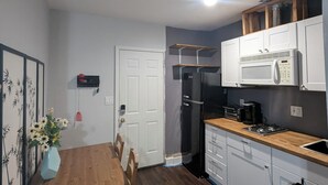 Cocina compacta con microondas, refrigerador y encimera de madera.