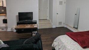 Un dormitorio con ventilador de techo, televisor, cama con ropa de cama floral y una colcha roja.