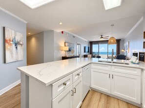 A modern kitchen with a large island, white cabinetry, and a view to the outside. - Beach Club D1606- K/Q/TwTwTwTw -Direct Gulf View  Beach  Pool - sleeps 8 in beds (Gulf Shores)