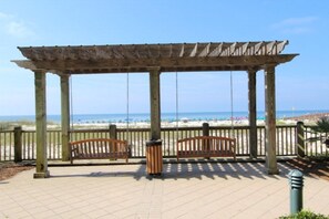 A wooden pergola with benches overlooking a beach.