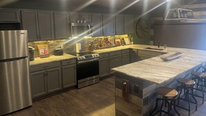 Una cocina moderna con electrodomésticos de acero inoxidable, una isla central con taburetes de bar y un techo de madera rústica.
