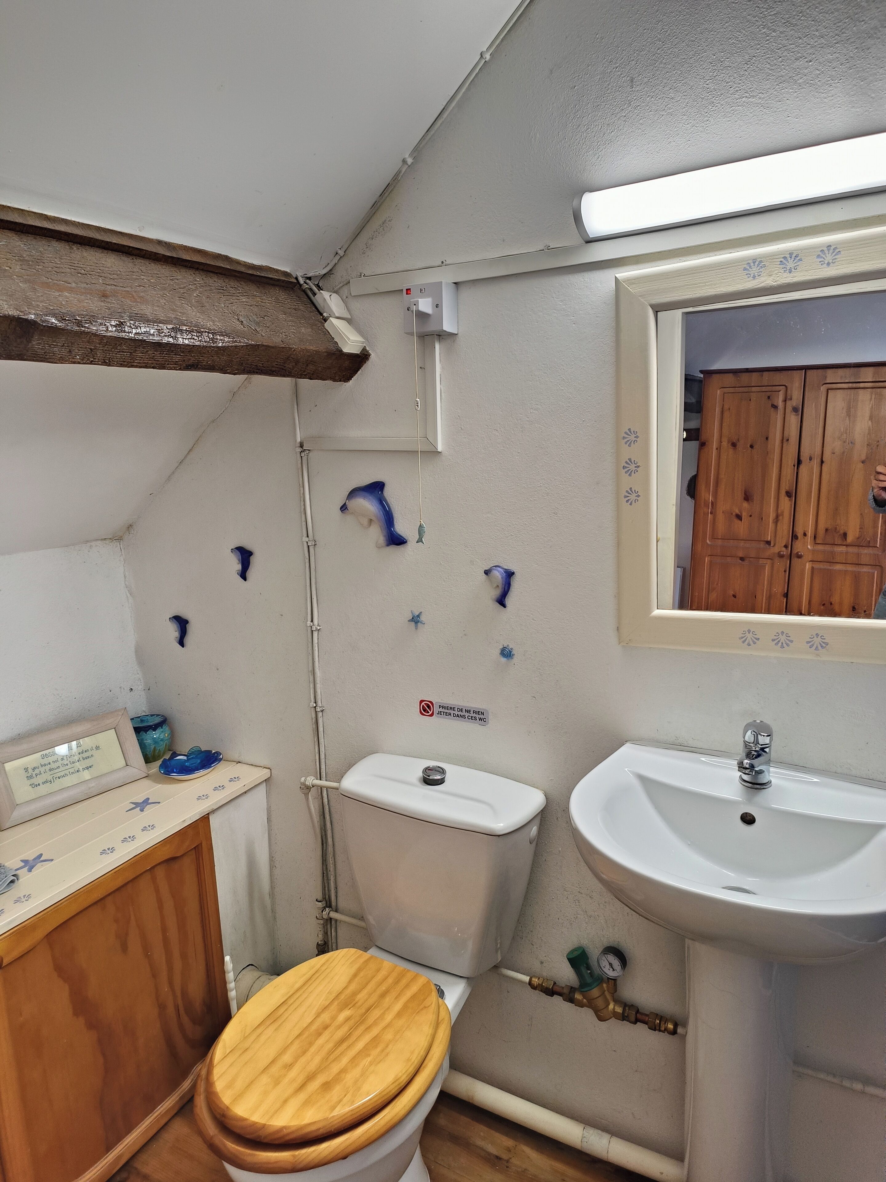 A small bathroom with a wooden toilet, a white sink, and a mirror above the sink.
