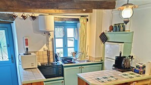 Une cuisine compacte équipée d’un évier, d’une cuisinière et d’un coin repas en bois.