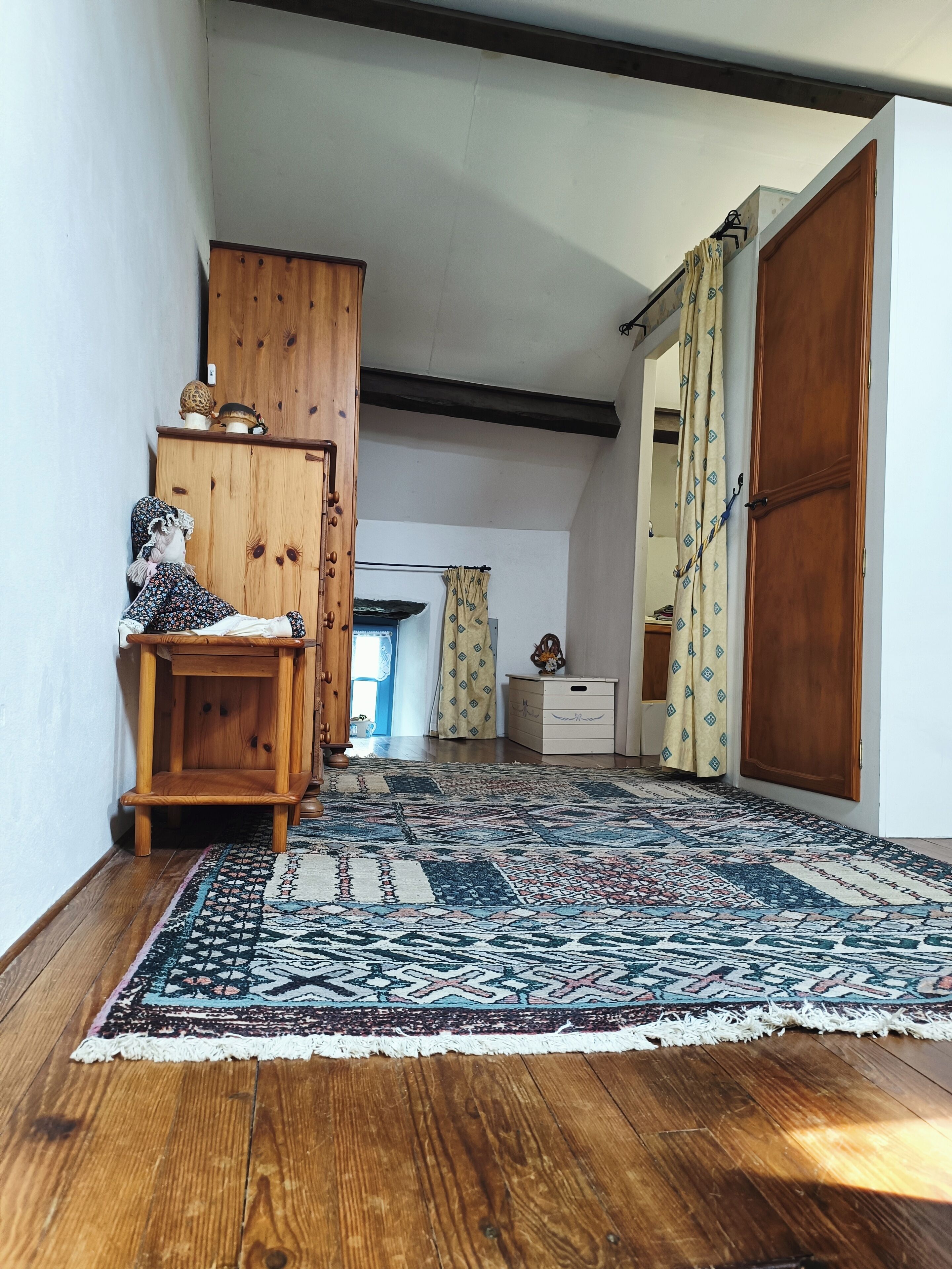 Un couloir avec un tapis à motifs, des meubles en bois et une armoire.