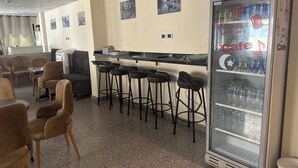 Um café com balcão, banquetas, frigorífico e sofá.