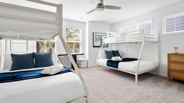 Un dormitorio con literas, ventilador de techo y vistas al exterior.