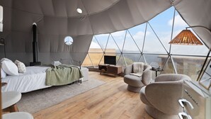 A modern tent-style bedroom with a bed, seating area, and a TV. - Hot Tub Dome with Epic Ridge Views- Hickory Heights (Stanton)
