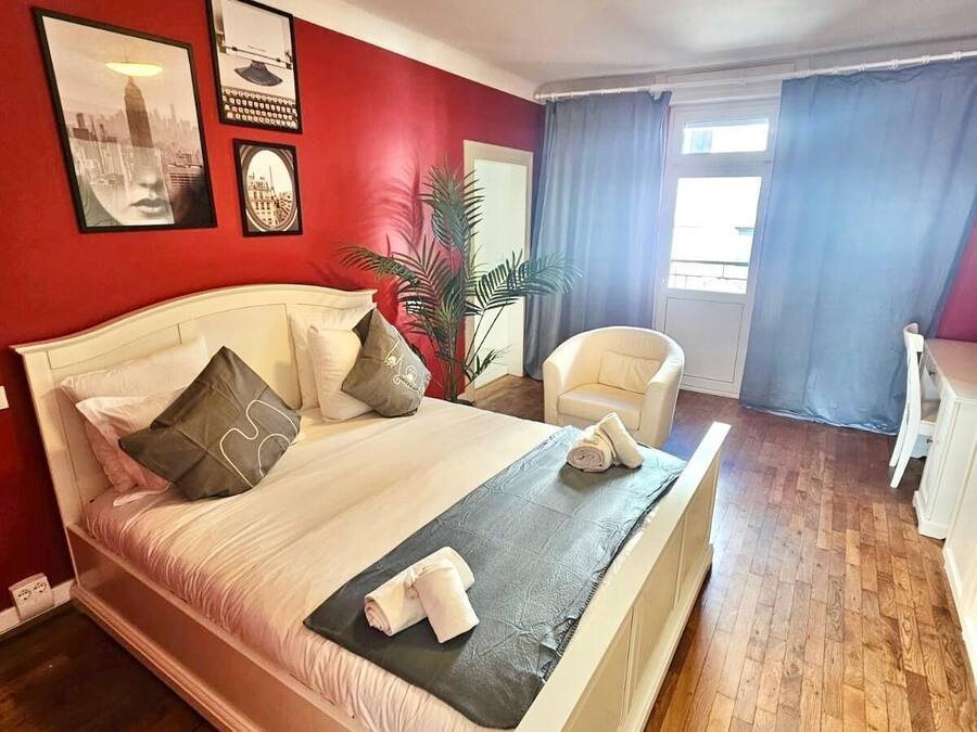 A neatly arranged bedroom with a large bed, a chair, and a desk.