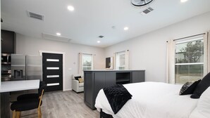 Ein modernes Schlafzimmer mit Bett, Schreibtisch und einer Küchenzeile.