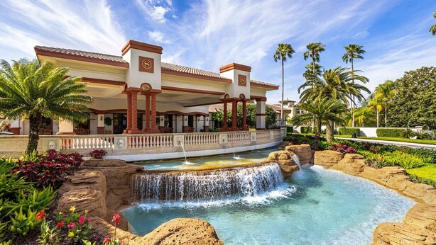 Un resort con piscina, palmeras y una cascada.