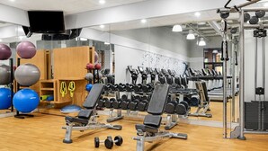 Un gimnasio con equipo de ejercicio, cintas de correr y pesas.