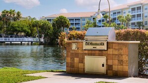 Zona de parrilla al aire libre con vista a un cuerpo de agua y un edificio al fondo.