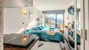 Quarto moderno com cama, escrivaninha e televisão.