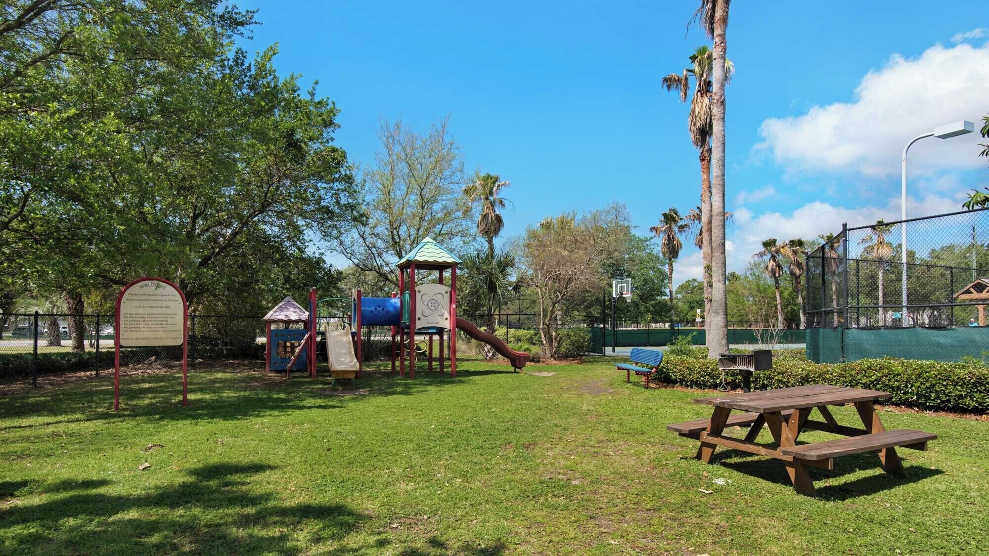A playground with a slide, a climbing structure, and a basketball hoop.
