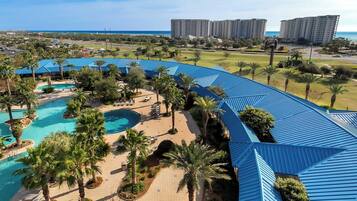 Un resort con una piscina grande, palmeras y vista al océano.