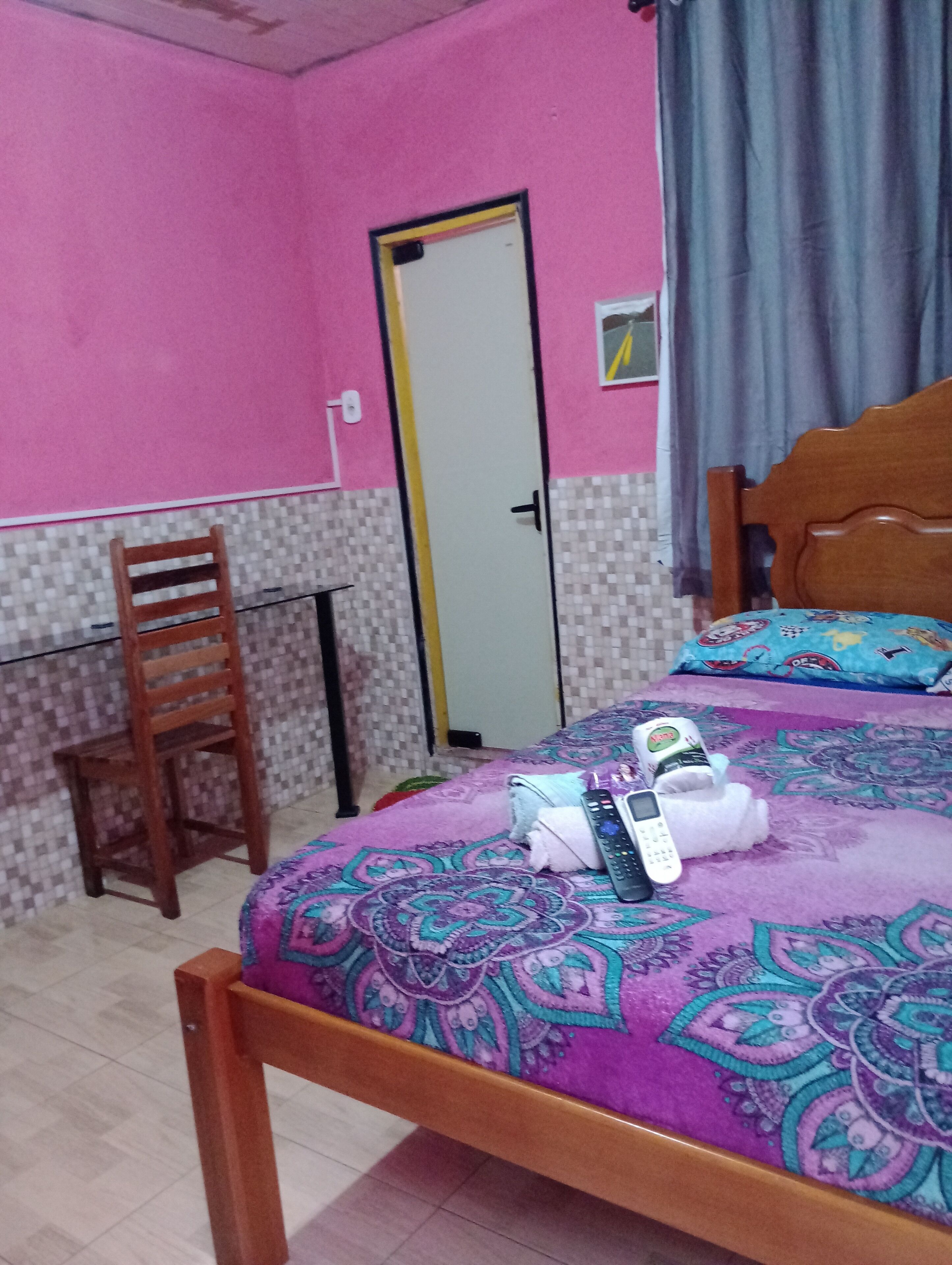 Ein Zimmer mit einem Bett, einem Sessel, einem Schreibtisch und einer Tür.