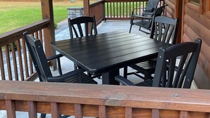 A wooden deck with a table and chairs, surrounded by a wooden railing. - Pine View Retreat | Walk to Lake | Game Room (Brantingham)