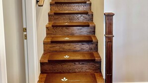 Un escalier en bois, doté d’une main courante et d’une petite rambarde en bois sur le côté.