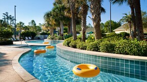 Une piscine à l’eau d’un bleu limpide, entourée de palmiers et bordée de carreaux.