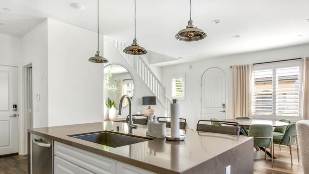 A modern kitchen with a central island, stainless steel appliances, and pendant lighting. - Coastal Village Townhome | Blocks2 Grandview Beach (Encinitas)