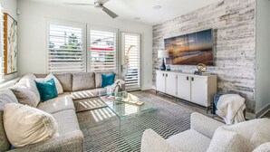 A modern living room with a sectional sofa, a glass coffee table, and a white cabinet. - Coastal Village Townhome | Blocks2 Grandview Beach (Encinitas)