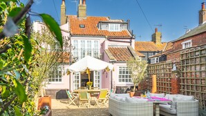 A patio area with wicker furniture, a table, and chairs under a white umbrella.