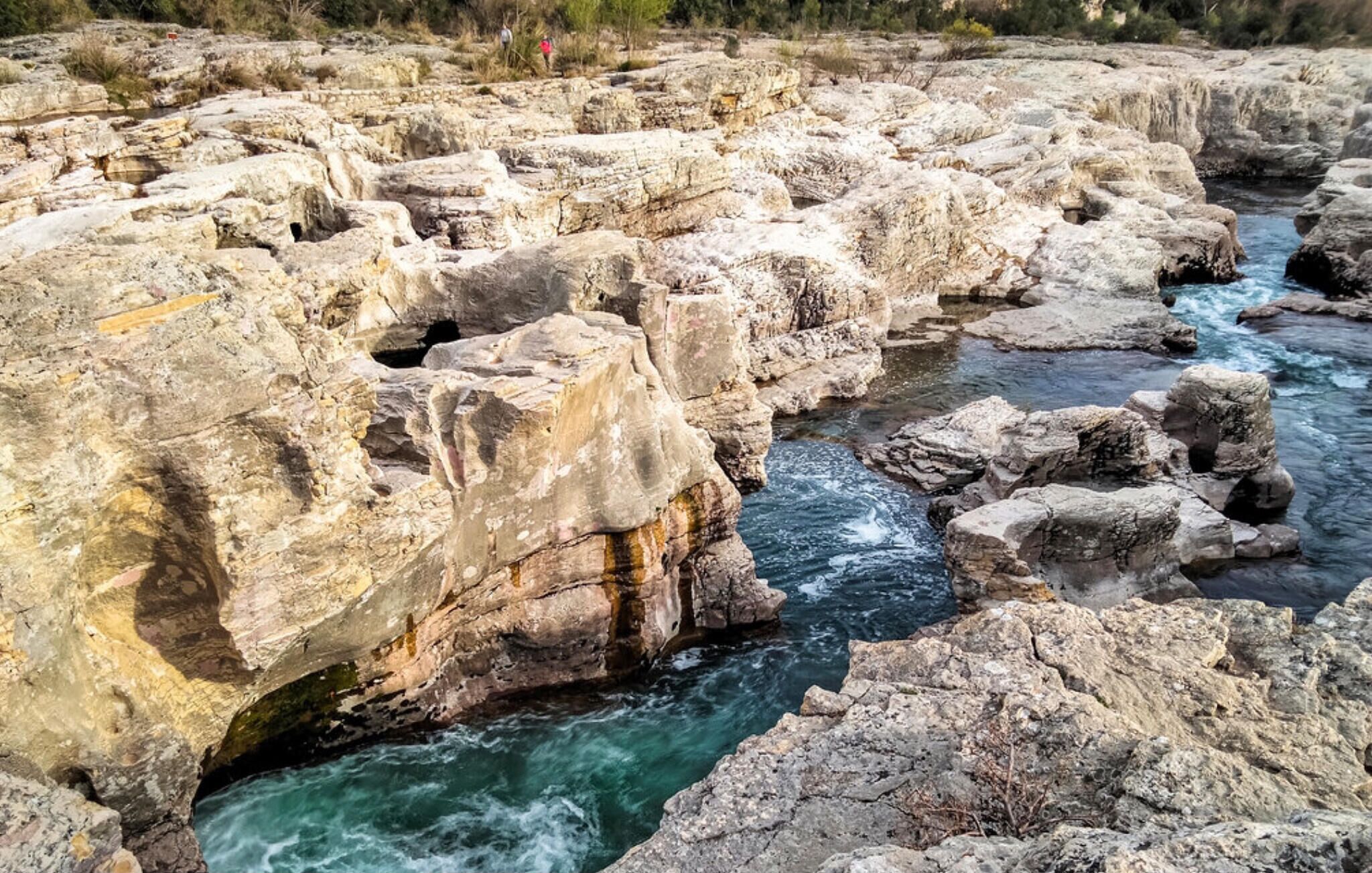 Ein felsiges Flussbett mit klarem, fließendem Wasser.