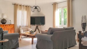 En stue med sofa, lænestol, sofabord, fjernsyn og dekorative genstande.