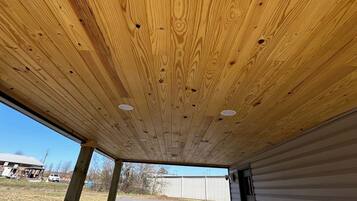 A ceiling with wooden panels and recessed lighting.