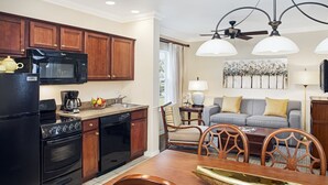 A compact kitchen with modern appliances, a dining area with a wooden table and chairs, and a living room with a sofa and a painting on the wall. - Cozy 1BR Villa at Sheraton PGA Resort Near Golf & Florida Attractions (Port St. Lucie)