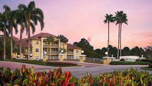 A hotel with a two-story structure, a balcony on the second floor, and a landscaped entrance with palm trees. - Cozy 1BR Villa at Sheraton PGA Resort Near Golf & Florida Attractions (Port St. Lucie)