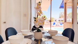 A dining table set with white plates, bowls, and a vase of orchids. - Waterfront Florida Vibes and Views - King Bed (Fort Lauderdale)